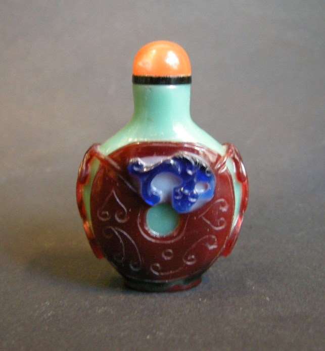 Glass snuff bottle overlay 3 colors on green carved and decorated with a coin